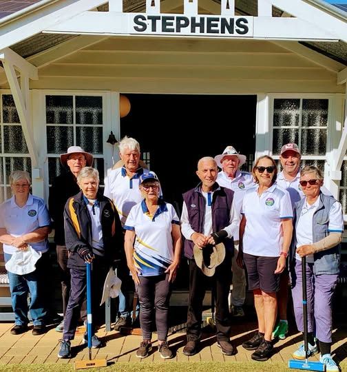 Nine people pose with croquet mallets in front of a clubhouse labeled "STEPHENS."